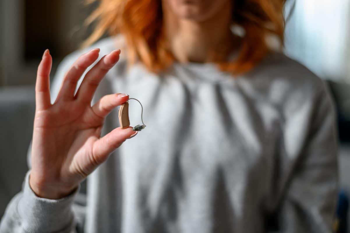 Woman hands holding a hearing aid
