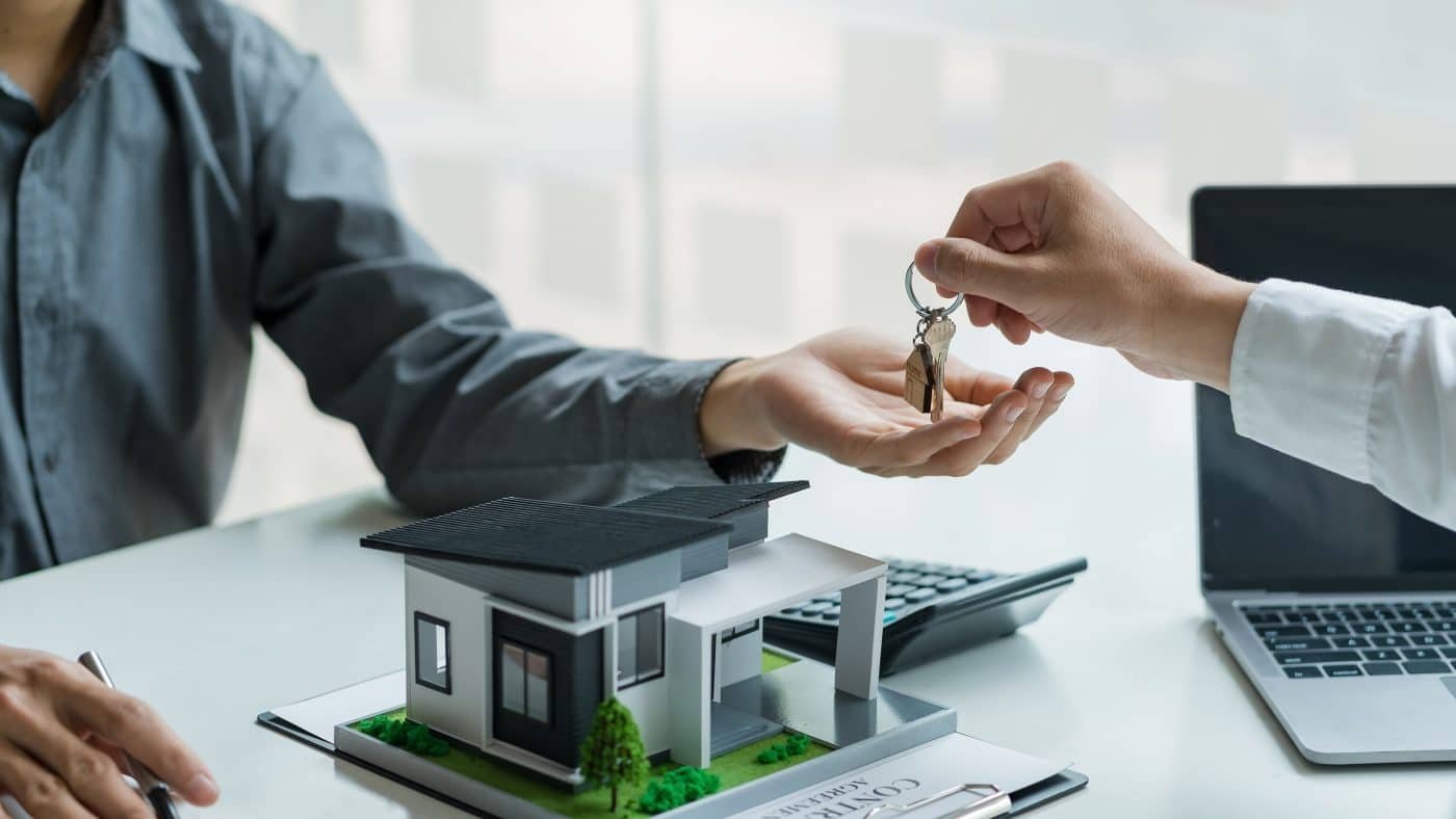 Real estate agent hand over the house key to customers after sig